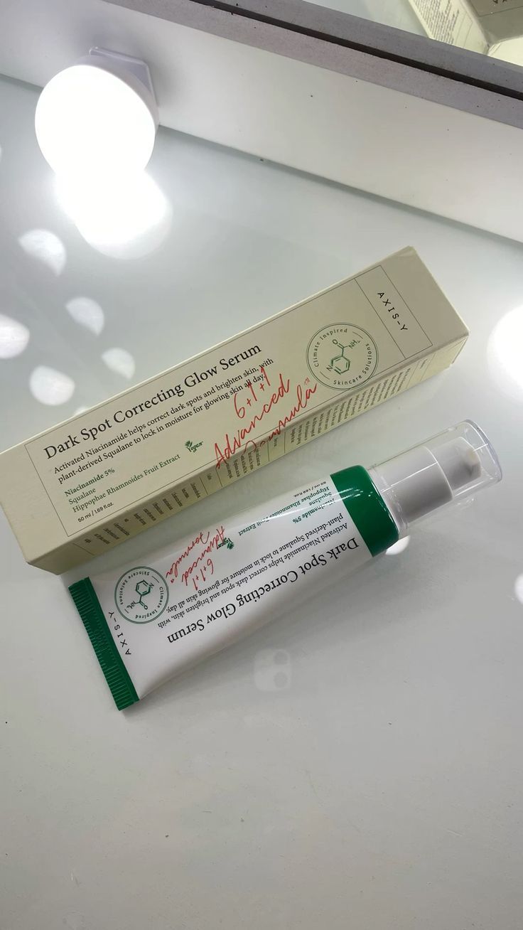 Axis-Y Dark Spot Correcting Glow Serum in its packaging on a reflective surface with soft lighting.